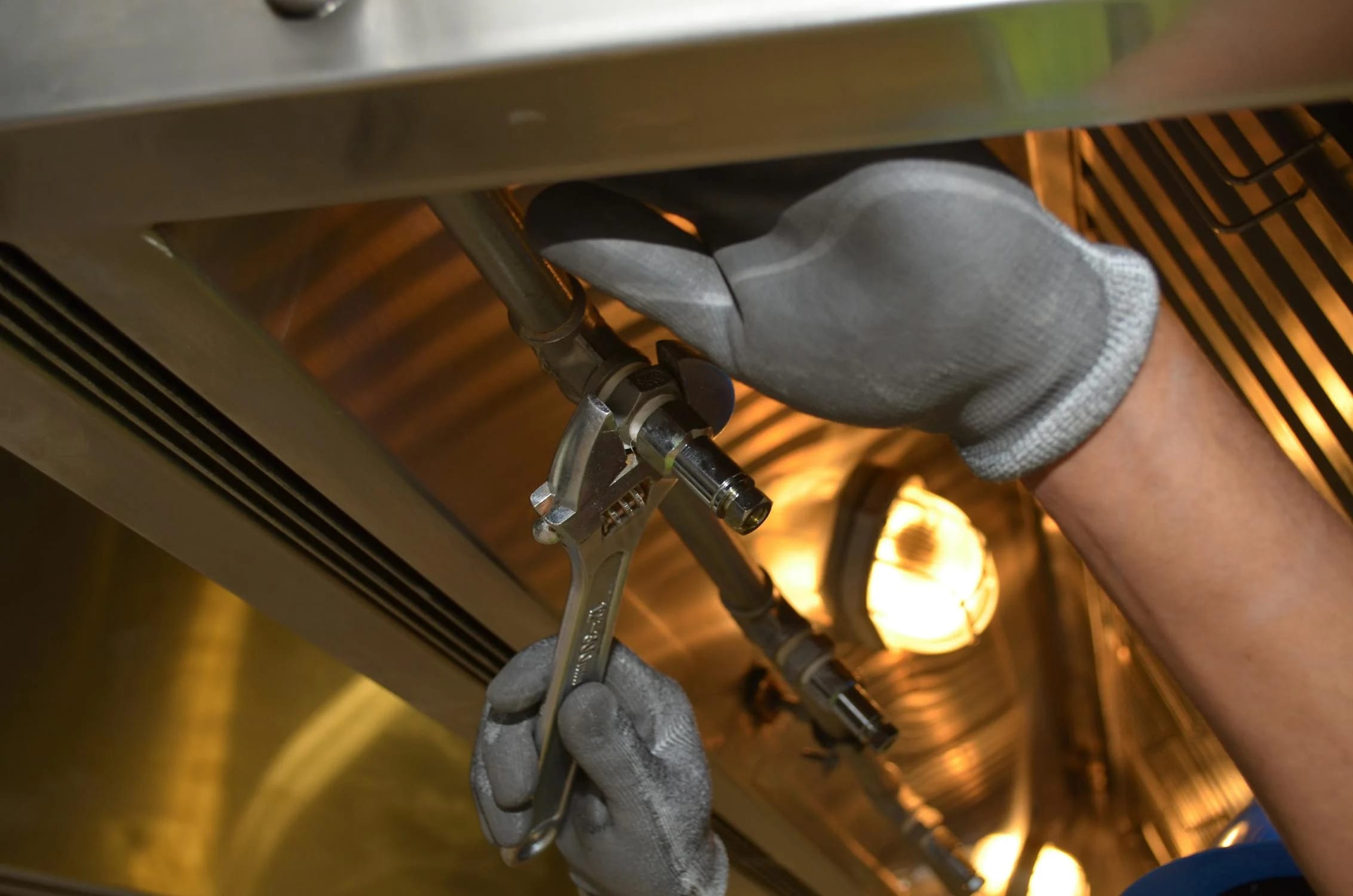 A close-up of a man using a spanner to work on plumbing fixtures, representing professional plumbing service.