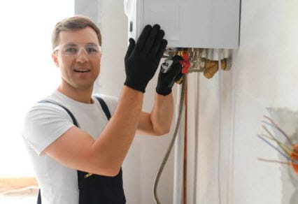 A plumber fixing a hot water heater, demonstrating essential maintenance and repair techniques for reliable plumbing systems